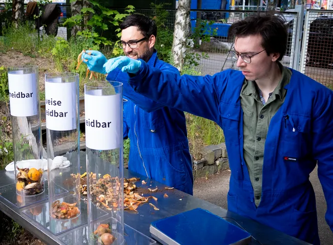 Aus Lebensmittelabfällen werden Biogas und Flüssigdünger. Steffen Walk (links) und René Hansen (rechts) sortieren den Abfall, bevor er geschreddert wird und in die Anlage kommt. Foto: Stephan Dublasky