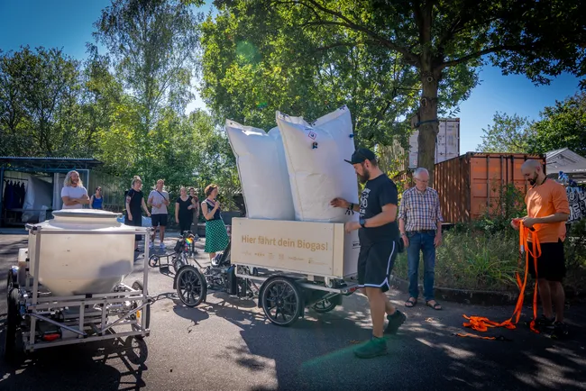 Die beiden Säcke mit Biogas werden auf einem Lastenrad festgezurrt. Foto: Stephan Dublasky